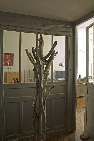 Pour créer une mezzanine sur toute la longueur de la pièce à vivre, il a fallu rehausser les plafonds et faire de nouveaux parquets. L’entrée isole la pièce à vivre et s’occulte grâce à des stores. Elle a été réalisée avec des matériaux de récupération.