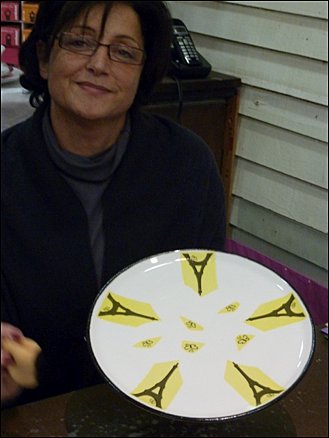 Patricia a posé les chromos (décalcomanie) des tours Eiffel qui vont cuire à 800° ; le jaune disparaît  et fixe le dessin. PETIT MODÈLE AU SINGULIER