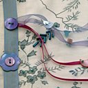 Décorer les motifs de  boutons, de perles et  de feuilles brodées.