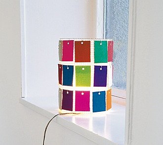 Un luminaire grillagé recouvert de petites cartes en papier crêpon