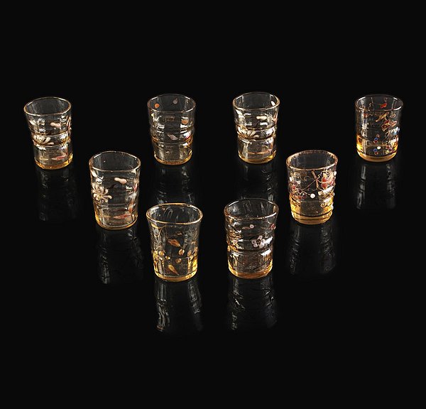 Suite de 8 verres à liqueur signés Emile Gallé. Epreuve de tirage industriel en verre fumé transparent. Décor de fleurs des champs. Emaillé à chaud à rehauts d'or. Vers 1900. Hauteur : 6 cm. 1000/15000 €
