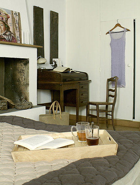 De l’autre côté de la cheminée, un élégant petit bureau à cylindre renferme ses petits secrets, album de photos Comptoir de Famille, sur le lit mugs Arc International.