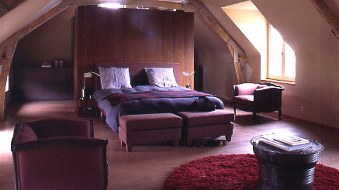 Comme une immense tête de lit, la cloison en palissandre des Indes annonce le grand dressing. Mobilier sur mesure par Debuysser pour LP décoration, fauteuil et bout de lit Styldécor, lustre Ochre. Sur le lit draps Eden Park plaid Zoeppritz