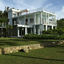 Le bâtiment bleu est ouvert sur de larges terrasses qui offrent une magnifique vue sur l’océan. Le jardin planté d’orchidées rares, de fougères arborescentes, de bambous et de palmiers laisse de vastes espaces plantés d’herbes descendant jusqu’à la grève