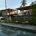 Entourée d’un chemin de teck, la piscine est flanquée de lits de repos en bambou traditionnels, ici revisités en lits de piscine, coussins en soie naturelle Tendance Khmère
