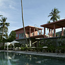 Entourée d’un chemin de teck, la piscine est flanquée de lits de repos en bambou traditionnels, ici revisités en lits de piscine, coussins en soie naturelle Tendance Khmère