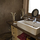 La salle de bains dont les murs et la crédence sont revêtus d’un Tadelakt anthracite, est ouverte sur une petite cour bien claire qui lui apporte la lumière nécessaire. Lampes Bleu Nature