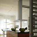 Le grand comptoir de 7 m s’étend d’un bout à l’autre de la cuisine ouverte. Il est souligné de granit Nero flammé. Les deux éviers se font face. Les grands placards et tiroirs contiennent toute la batterie de cuisine. Suspensions Philip Starck chez Flos