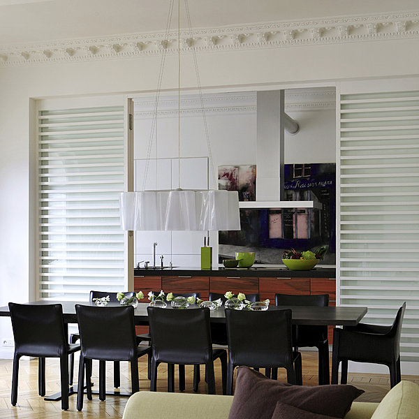 Table B&B chez Maxalto, chaises « Cab » Cassina, suspension Logico Artémide. Au fond sur le plan de travail, saladiers et bloc couteau Ekobo. Derrière la hotte, tableau de Jorge Martino