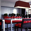 La double table haute de salle à manger en métal laqué et verre sablé est entourée de banquettes hautes et surmontée de luminaires, le tout fabriqué sur mesure par Exsud