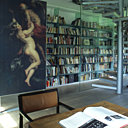 Située au premier étage, la bibliothèque regorge d’ouvrages d’art. La reproduction d’un tableau de Rubens ajoute une note baroque. A droite, la cage d’escalier en verre laisse filtrer la lumière