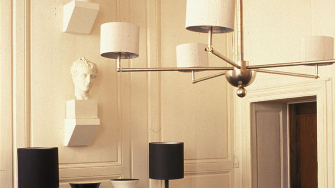 La table ronde centrale en chêne foncé est éclairée par un lustre en métal prototype de la collection Pii La table ronde centrale en chêne foncé est éclairée par un lustre en métal prototype de la collection Pii