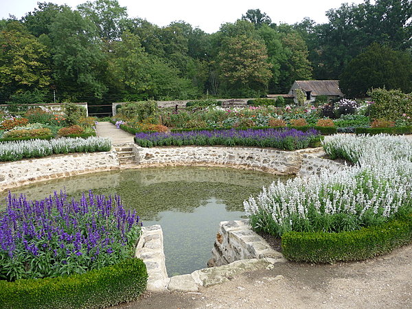 Bordé de fleurs entourées de buis taillés, le bassin central du potager