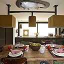 A l’heure du déjeuner. Suspension, table, Evasion 55, tabourets tracteurs chinés, chaises verte, Emmaüs, assiettes creuses et saladier, Home Autour du Monde.