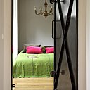 Derrière une ancienne porte de cale, la chambre des parents. Dessus de lit et coussins rose, Caravane.