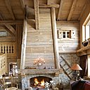 Une immense cheminée toute de bois vêtue  donne toute son authenticité  au salon : sous une charpente en bois d’Epicéa et bois de récupération, de grands canapés Nobilis sont  recouverts de tissus écossais Pietraneck, Squawvalley et de plaids Arpin.