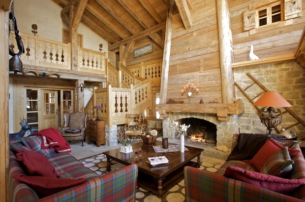 Un mélange de matériaux anciens bois épicéa et pierre pour un espace qui reste cosy . Canapés Nobilis recouverts de tissus écossais, Pietraneck , Squawalley, plaids, Arpin, sur la table basse, vase « Antartic », Sia et vase à plusieurs branches, Coming, B.