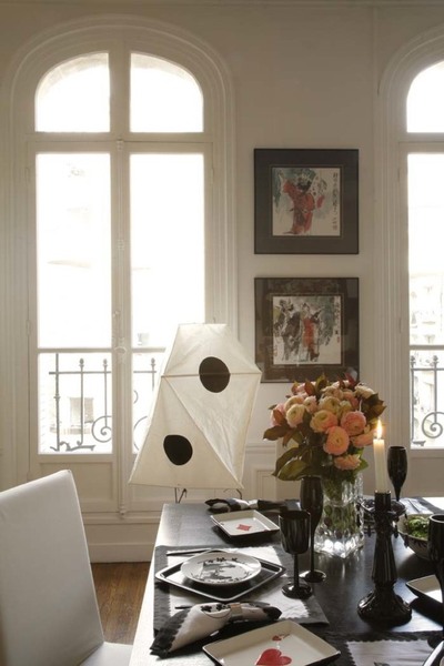 Un repas en noir et blanc : sur un table Philippe Hurel, assiettes «style « Pompadour », La Chaise Longue, verres à pied, Deshoulières, flûtes, sets, serviettes, bougeoirs, Potiron, couverts et assiettes noires de présentation, Ikea, petits plats « cartes à jouer », Galerie Lafayette Maison ( marque mirage). Chaises, Habitat,  lampe en papier, Isamu Noguchi, Sentou galerie, les deux tableaux entre les fenêtres achetés à Hong Kong.