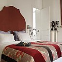 Une chambre en rouge et blanc : tête de lit, Maison Fassier, taies d’oreiller parme chemise de nuit noire, Château de Vaux, dessus de lit blanc, Mis en Demeure, dessus de lit fleurs, Linvosges,  abat-jour, Impromptu.