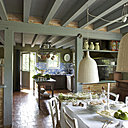 Une cuisine spacieuse qui a su gardé son cachet. Sur une table chinée, Village Notre Dame, un chemin de table blanc Naaj, CSAO vaisselle, Vermont Frères, buffet, village Notre Dame, posés dessus objets en verre, Lieux, habitat, RKR, chaises, Habitat, suspensions , Ikea, ; dans la deuxième partie de la cuisine décorée de carreaux bleus, Sarreguemines, une table de drapier XIXème et un meuble de grainetier aussi du  XIXème transformé en vaisselier.