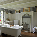 Blanc, gris et bois ciré pour une salle de bains toute en douceur. Autour d’une ancienne baignoire en fonte chinée, un miroir, Village Notre Dame, des porte-serviettes, RKR, des rideaux, Habitat  et des études au fusain du XIXème.