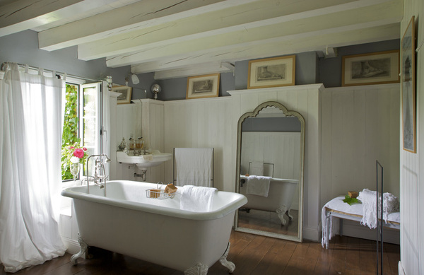 Blanc, gris et bois ciré pour une salle de bains toute en douceur. Autour d’une ancienne baignoire en fonte chinée, un miroir, Village Notre Dame, des porte-serviettes, RKR, des rideaux, Habitat  et des études au fusain du XIXème.