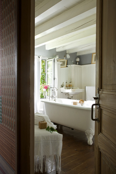 La salle de bains qui joue sur les tons de gris et de blanc profite des senteurs du jardin. Baignoire ancienne en fonte, rideaux, Habitat, porte-serviette, RKR, linge italien de Capri, papier peint couloir, patchwork papier pochoir XIXème, Dugrand.