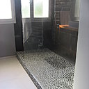 Galets naturels pour le sol de la douche et grandes dalles de carrelage gris foncé pour les cloisons