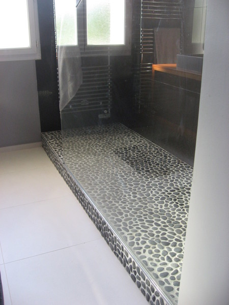Galets naturels pour le sol de la douche et grandes dalles de carrelage gris foncé pour les cloisons