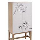 Quelques branchages japonisants ornent les portes du cabinet Brixham. Panneau de particules plaqué chêne. 70 x 140 x 40 cm. 400 €.