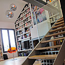 Une grande bibliothèque sur mesure en médium peint en blanc s'intègre parfaitement à l'architecture des lieux. Fauteuil Eros de Kartell, dessiné par Philippe Starck.