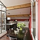 Ce patio façon verrière sert de transition entre le salon, la salle à manger et la cuisine. Verrière métallique, Soudure Express, charpente et bardage bois, Mr Taris, table, Bois&Chiffons, miroir, Chehoma, chaises, Starck, cuisine, hôte et suspension, Ikéa, tabourets, Alinéa, parquet d’origine.