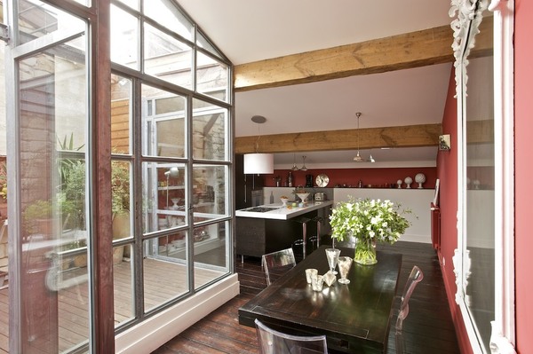 Ce patio façon verrière sert de transition entre le salon, la salle à manger et la cuisine. Verrière métallique, Soudure Express, charpente et bardage bois, Mr Taris, table, Bois&Chiffons, miroir, Chehoma, chaises, Starck, cuisine, hôte et suspension, Ikéa, tabourets, Alinéa, parquet d’origine.