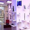 Des petites étagères blanches en saillie baignées d’un halo blanc et bleu viennent attirer l’œil du visiteur.