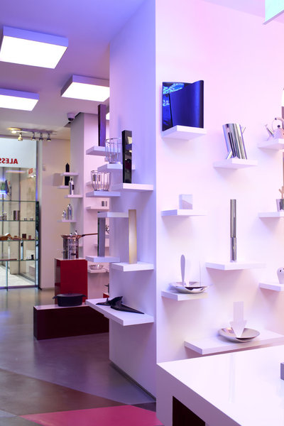 Des petites étagères blanches en saillie baignées d’un halo blanc et bleu viennent attirer l’œil du visiteur.