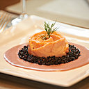 Le saumon bio est servi entouré de riz noir et d'une sauce crémeuse