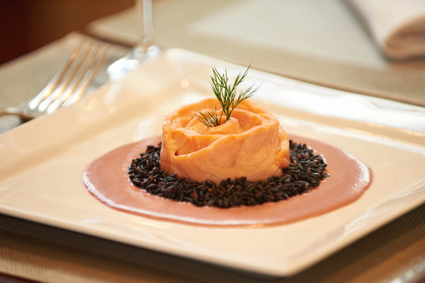 Le saumon bio est servi entouré de riz noir et d'une sauce crémeuse