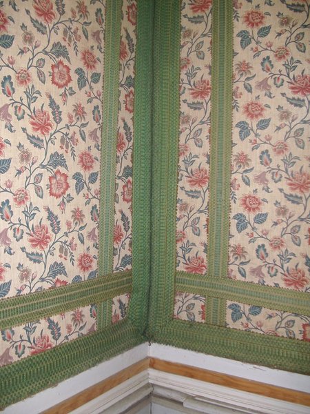 Deux largeurs de galons émeraude superposés s’entrecroisent pour structurer les murs d’une des chambres du château de Fontaine-Française recouverts de tapisseries à l’indienne. La géométrie des bandes de galons contraste avec les courbes délicates des fleurs et répond à l’inclination luxueuse du lieu.