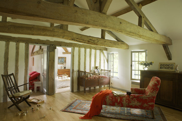 Le premier étage dessert deux chambres et une grande pièce faisant office de dortoir quand la maison est remplie. Méridienne de famille et lit de bébé  recouverts d’une toile de Jouy, Toto Solde, fauteuil basque, buffet de cuisine, plaid, Ikéa.