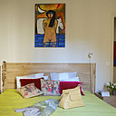 Dans cette chambre inondée de soleil, sur un tapis AMPM,  une superbe reproduction de la chaise longue « poney » signée Le Corbusier , un dessus de lit aux tons du Midi , couleur anis, Caravane, tringle, Leroy Merlin, rideaux et tapis , AMPM. Le couloir de l’entrée donnant sur la salle à manger, affiche une certaine sobriété, console AMPM, miroir The Conran Shop, peinture, Guérin, applique, Habitat.