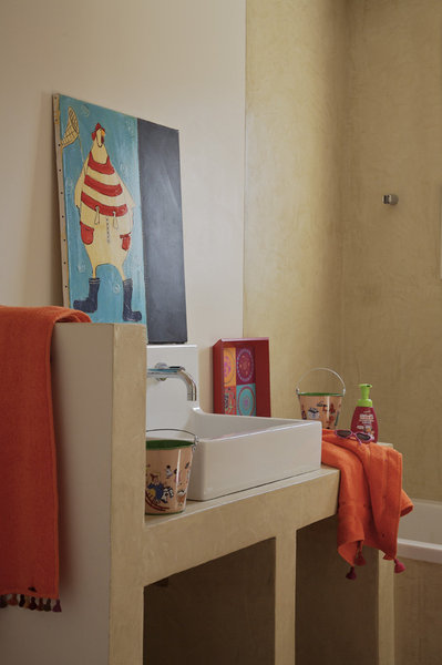 Une salle de bains couleur pierre, en rythme avec la nature, sépare les deux chambres d’enfant. Serviettes de bains Mia Zia, Koba, enduit béton, Mercadier.