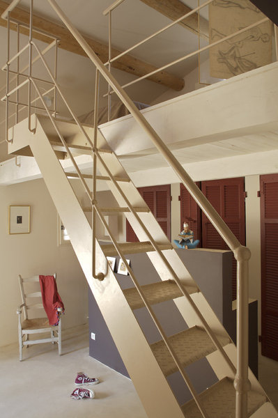 Une grande pièce  aménagée façon loft, abrite la salle de bains et la chambre des parents. Pour lui donner un air provençal, des volets chinés ont été remontés en porte de placards peints en « Eating Room Red », Farrow&Ball, côté salle de bains ; sol, enduit béton ciré couleur amande, Mercadier, escalier fait sur mesure et peint en « Smoked Trout », Farrow&Ball, Mercadier.