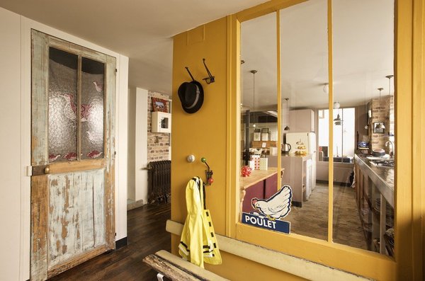 Une petite entrée soulignée de jaune délimite l’espace. Couleur safran Emery&Cie, banc récupéré dans une ancienne crèche, portemanteaux, brocante Alasinglinglin, affiche poulet, Urban Outfitters.