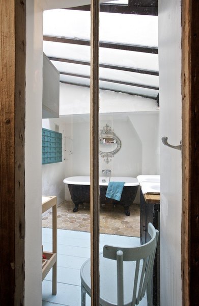 Afin de profiter de la lumière, une fenêtre a été créée entre la douche et la salle de bains ; meuble bleu, Atelier 154, baignoire d’origine, miroir chiné au Mexique.