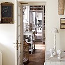 Une entrée lumineuse, blanche et crème, aux détails charmants : horloge aux tons vieillis, petit tableau et luminaires stylisés aux accents campagnards.