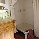 La douche aux pieds travaillés et aux rideaux blancs.