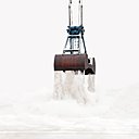Une benne délivrant un sable blanc qui se lie au ciel : solitude d’une action figée.