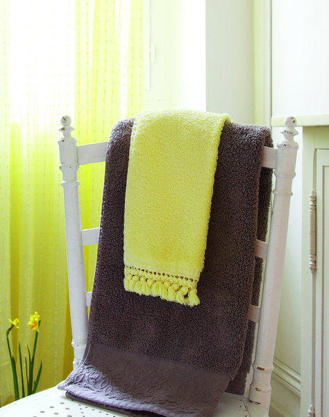 Des tons citron contrastant avec le gris pour une salle de bain lumineuse.
