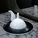 La cloche de porcelaine bombée posée sur l'assiette et la petite saucière laisse présager un met délicat concocté par Anne-Sophie Pic