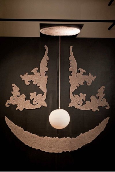 José Levy, Visage rond. Ce tapis fait appel aux savoir-faire conjoint des 2 manufactures. La suspension lampe nez est en porcelaine (35cm), le  travail des moulures est réalisé en laine.